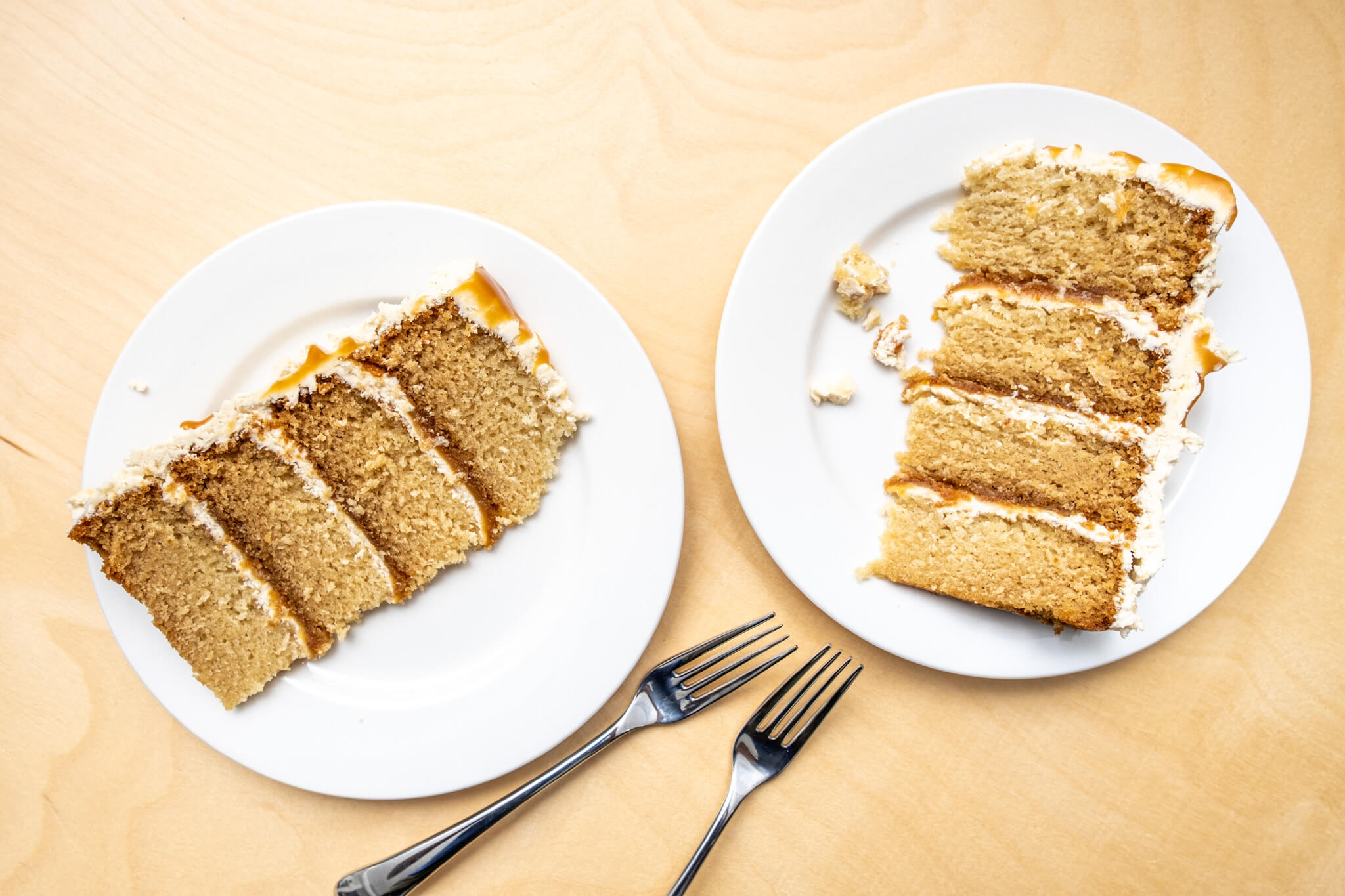 Two plates with slices of vegan caramel cake on a wood table