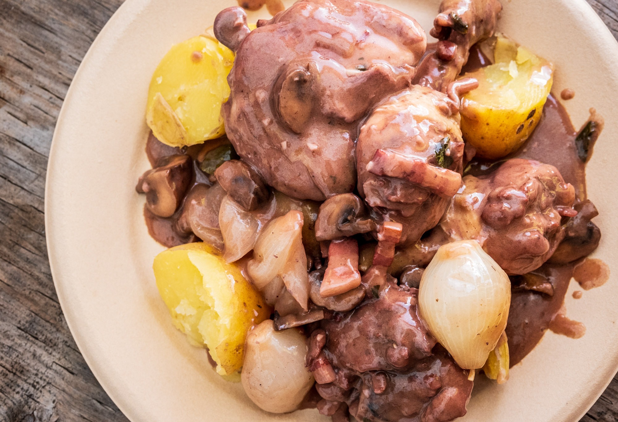 Plate of coq au vin served with potatoes, mushrooms and onions