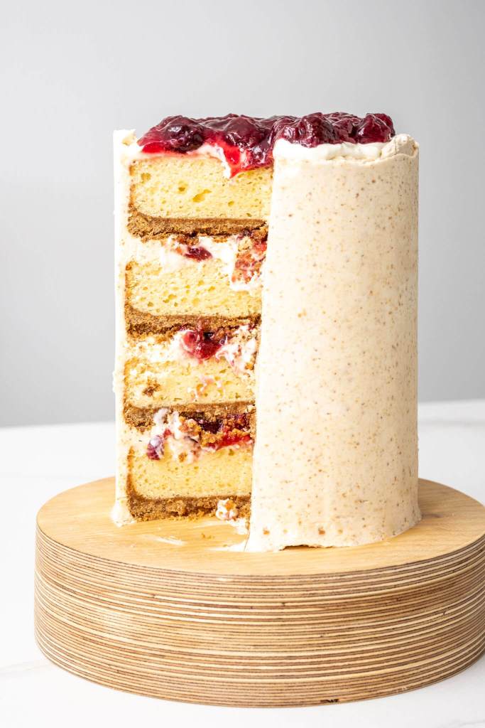 4 layer cake inspired by cherry cheesecake with graham crumb crust on each layer, cream cheese filling and sour cherry sauce