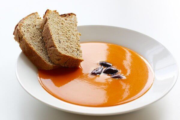 Cold tomato and red pepper soup with bread and olives